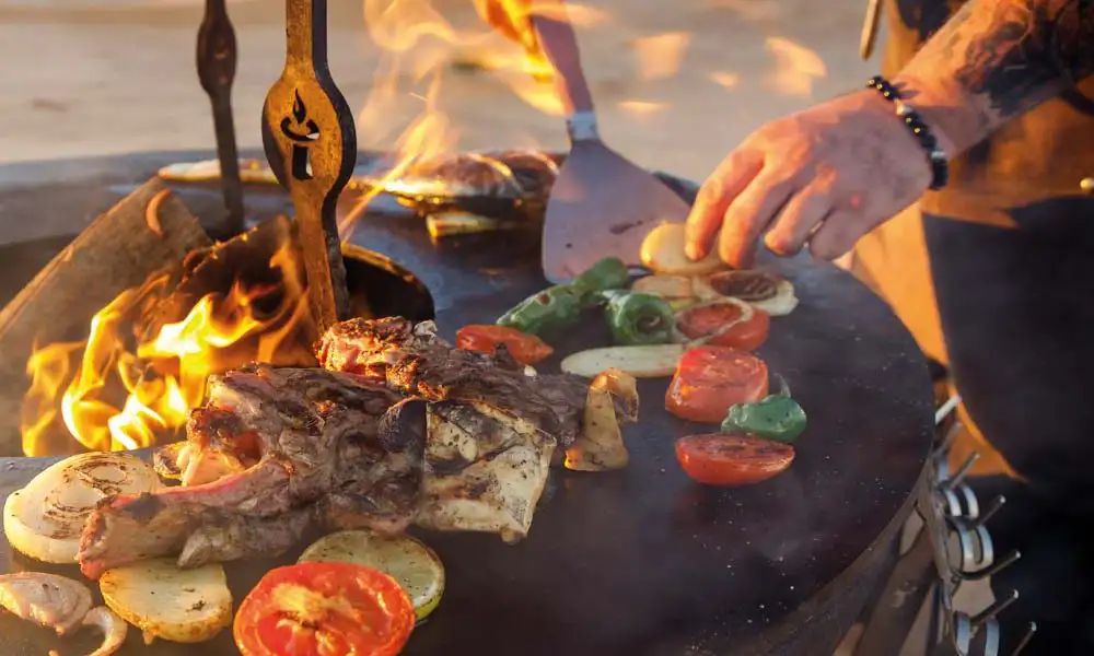 remundi-kulinarische-vielfalt-fisch-gemuese-topper-aufsatz-1000x600 Jemand wendet mit einer Grillspachtel Grillgut auf der Plancha-Platte