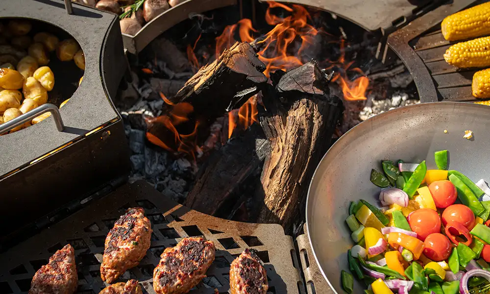 Modulgrill mit sechs verschiedenen Grillmodulen, die einen Ring ergeben und mit Fleisch und Gemüse belegt sind
