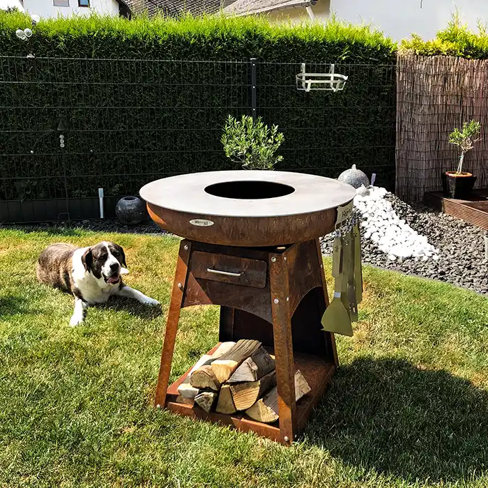 Remundi Zelos M im Garten auf Grasfläche stehend, dahinter ein liegender Hund