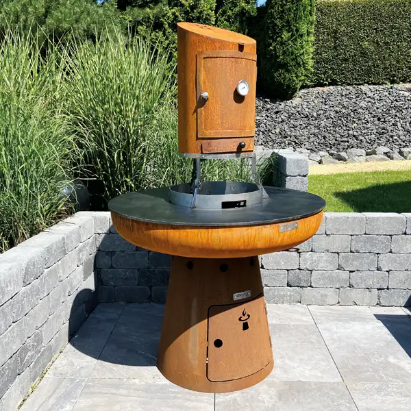 Der Smoker in Rostoptik mittig platziert über der Remundi Feuerstelle im Garten