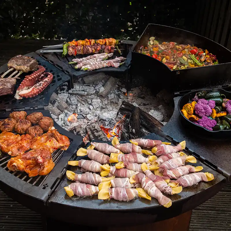 Modulgrill mit sechs verschiedenen Grillmodulen, die einen Ring ergeben und mit Fleisch und Gemüse belegt sind
