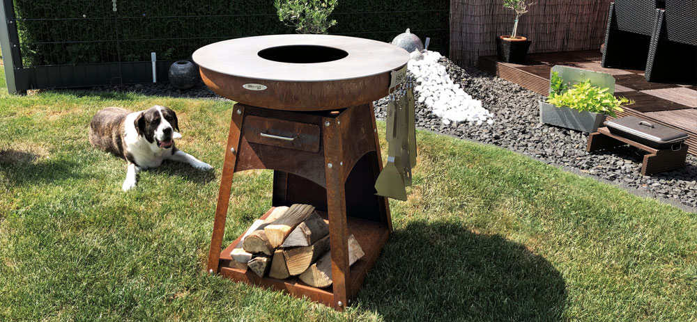 Remundi Zelos Feuerstelle im Garten daneben liegt ein Hund