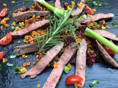 Aufgeschnittenes Flanksteak auf Cous Cous mit Minzjoghurt auf der Remundi Feuerplatte angerichtet