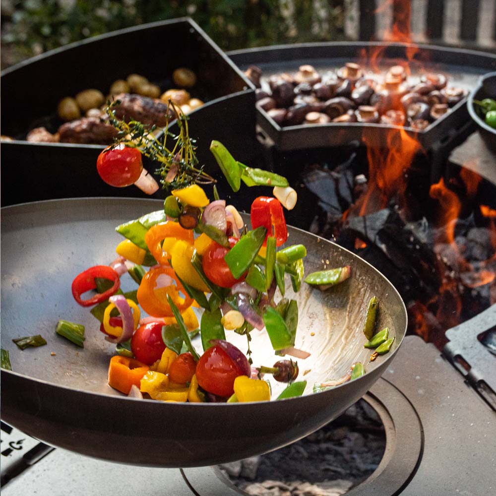 Grilled vegetables seared in the wok set on the fire pit
