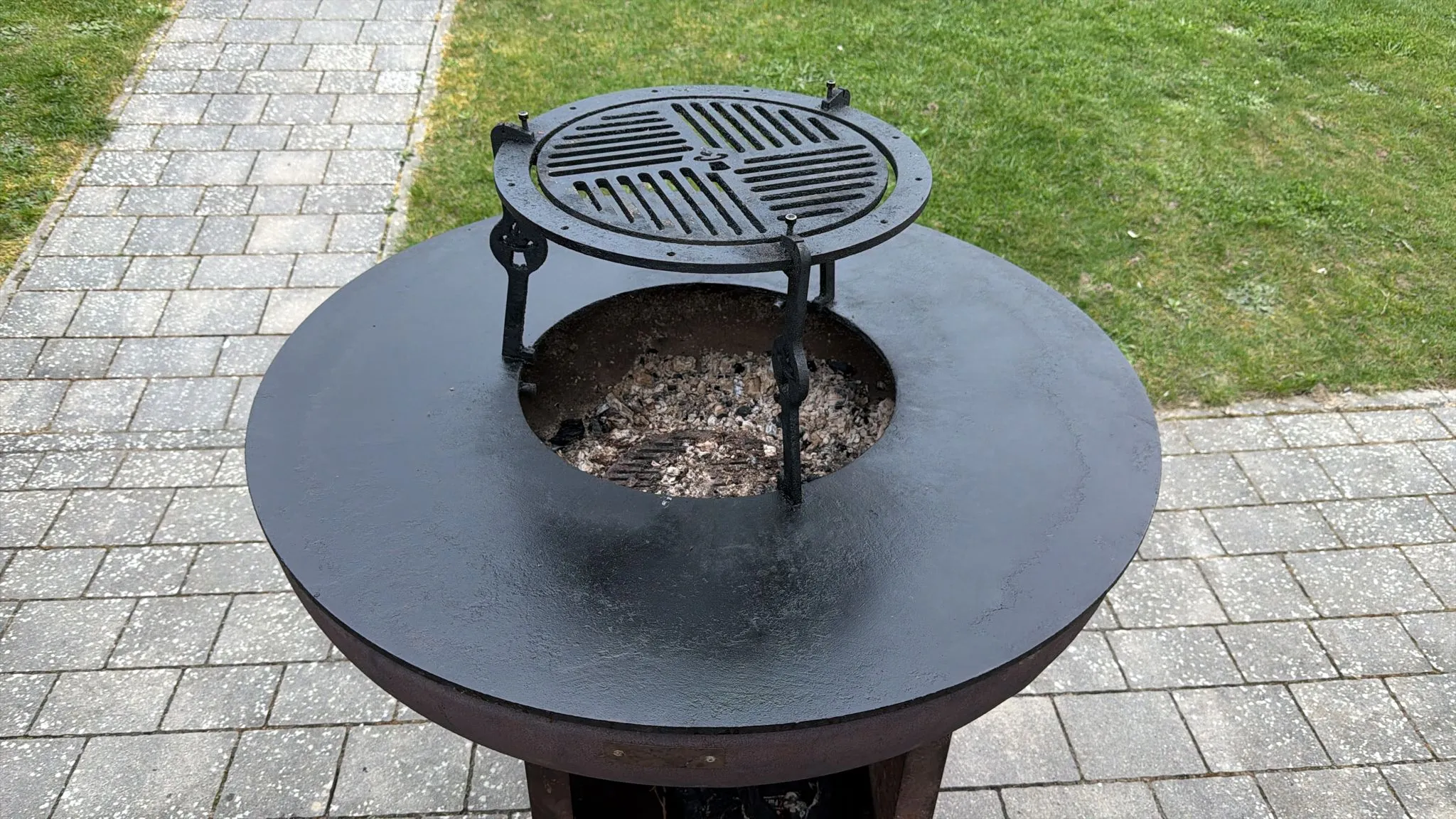 Eingebrannte Feuerplatte mit sichtbarer Patina nach einer Grillsession – die dunkle, gleichmäßige Oberfläche zeigt den natürlichen Antihaft-Schutz