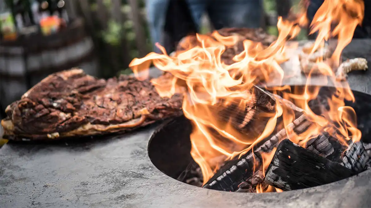 Detailansicht Grillplatte mit Brennholz und lodernden Flammen