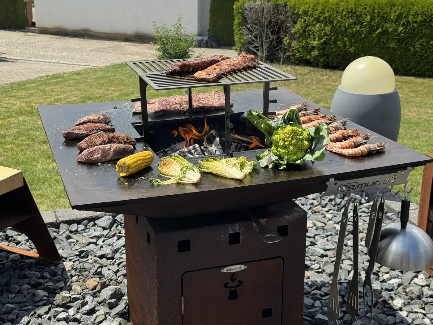 Remundi Cube Feuerstelle beim Grillen im Garten